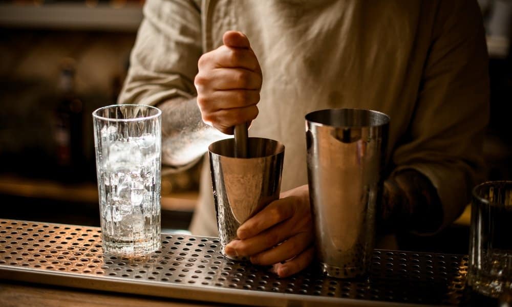 Un homme préparant du cocktail dans un shaker en inox