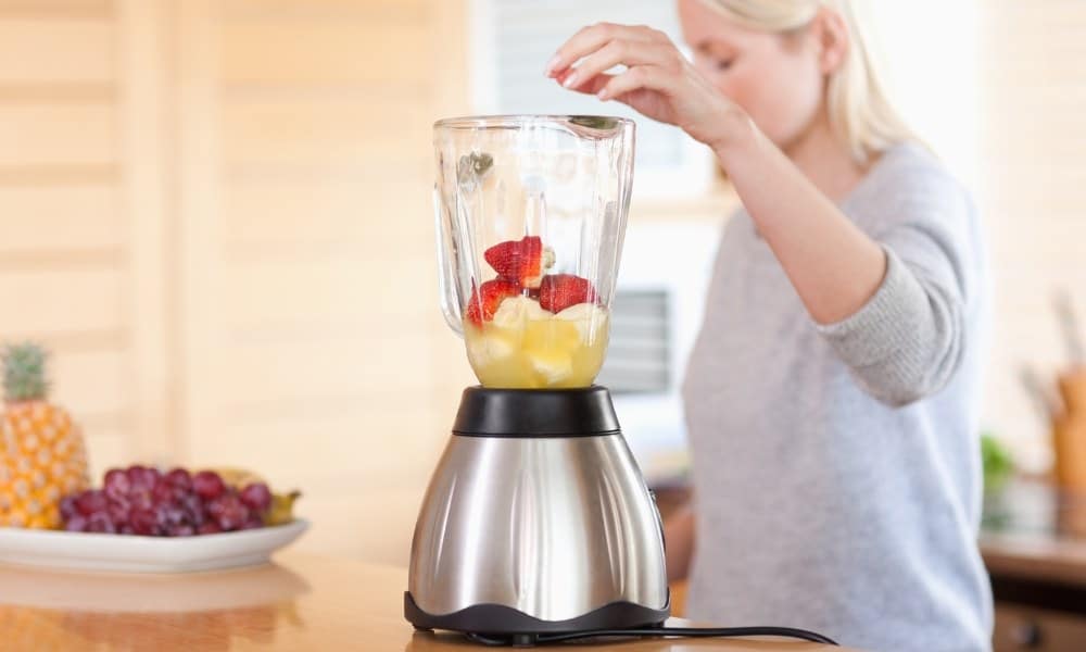 Une femme utilisant un blender pour cocktail