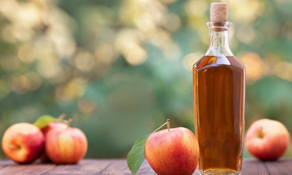 Bouteille remplie de cidre avec des pommes