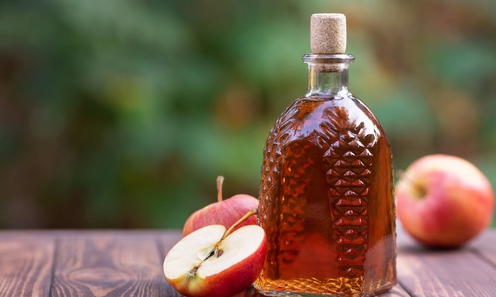 Bouteille remplie de cidre avec des pommes